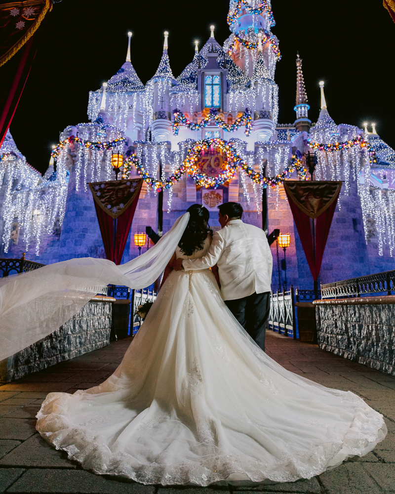 Disney Wedding castle portrait session at Disneyland with Christmas lights on Sleeping Beauty Castle
