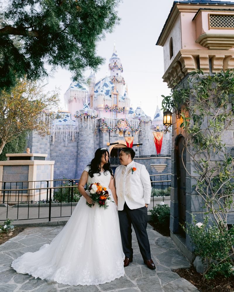 Bride and groom posing in front of Sleeping Beauty Castle during a Disney Wedding portrait session